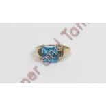 A 9 carat gold blue topaz and diamond dress ring, the square topaz between shoulders set with a trio