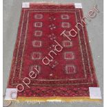 A 20th century red afghan rug, on a red ground with central diamond and square motifs