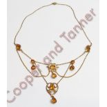 An Edwardian citrine and seed pearl festoon necklace, the round cut stones within leaf scrolls, with