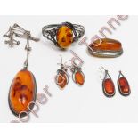 An amber set bangle; an amber pendant on chain; an amber brooch; and two pairs of amber earrings