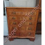 A serpentine chest of drawers, of five long with a pull out drawing table, 89cm high, 74cm long,