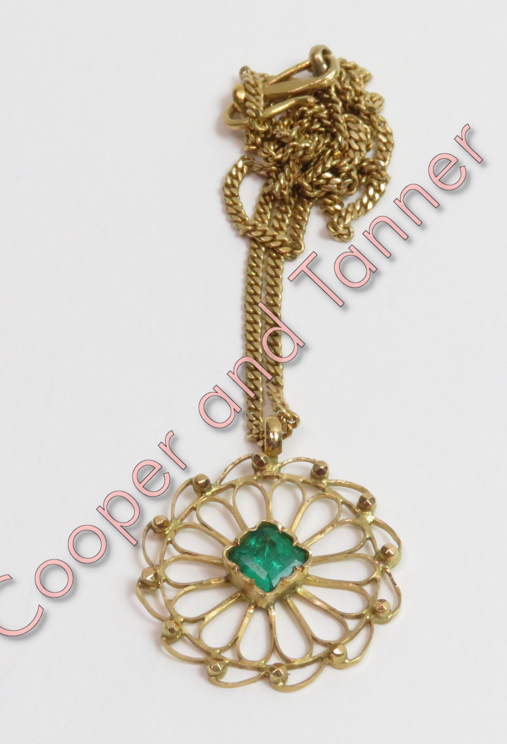 A single stone emerald pendant on a chain, the square cut stone to an openwork circular unmarked