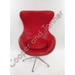 An egg chair upholstered in a red vinyl, after a design by Arne Jacobsen