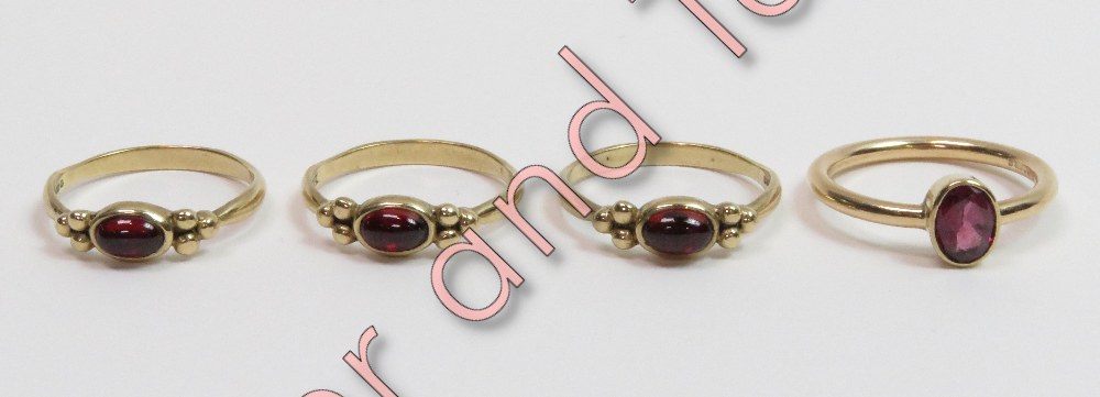 A trio of 9 carat gold single stone garnet rings, each set with a cabochon between a trefoil of