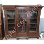 A late 19th/early 20th century oak breakfront glazed cabinet, raised on bum feet, with short