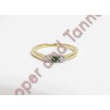 A three stone diamond and emerald ring, stamped '18ct Plat', finger size M, 2 g gross, cased