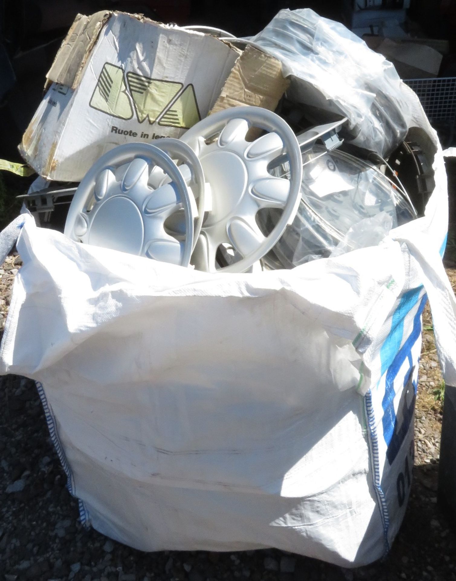 Large sack of new and used wheel trims as well as large black container also with used wheel trim