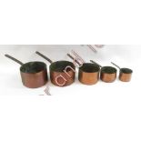 A graduated set of four late Victorian copper saucepans and a similar large pan, all with metal