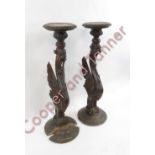 A pair of carved wood torcheres having circular tops supported on mythical beast pillar and carved