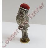 A metal pin cushion in the form of an owl on a tree stump, paste set eyes, monogrammed seal base,