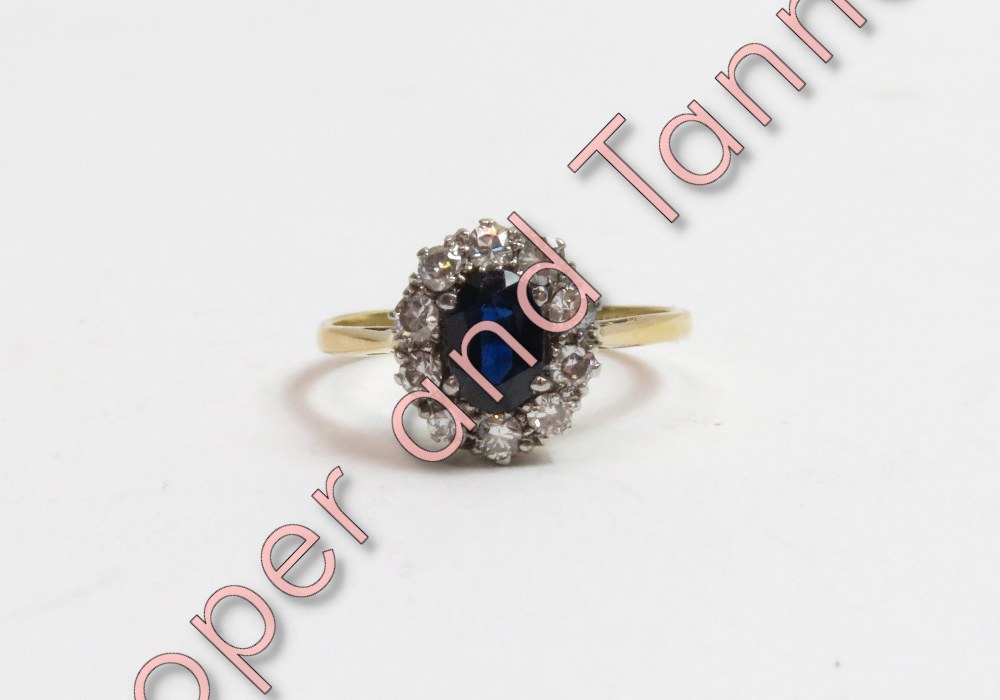 A sapphire and diamond cluster ring, stamped '18ct', the oval cut stone enclosed by ten brilliant