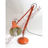 An orange painted metal angle poise lamp