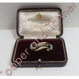 An Edwardian seed pearl and turquoise brooch, stamped '15ct', of double scroll form, 3.2 cm long,