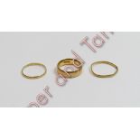 A plain 22 carat gold wedding ring; and two thinner wedding rings; 8 g gross