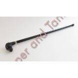 An ebonised walking cane with moulded dogs head handle having inset glass eyes, 91cms long