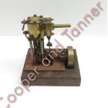 A small engineered brass working model of a single cylinder pump engine mounted on a wood base,