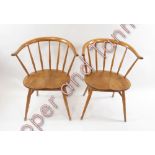 A pair of Ercol lightwood stick back chairs with curved cresting rails and shaped seats