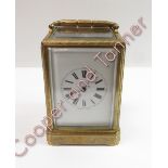 An ornate engraved gilt brass 2 train 8 day carriage clock, striking on bell. The white enamel