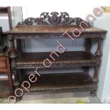 A late Victorian carved oak three tier dumb waiter with openwork carved foliate back, turned