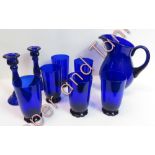 A Bristol blue water jug and six tall glasses with shaped bases and a pair of candlesticks of spiral