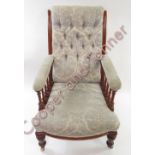 A late Victorian upholstered open arm chair with buttoned back, the arms supported by turned pillars