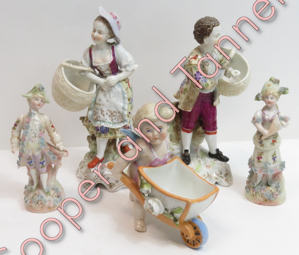 A pair of 19th Century German figures of a boy and a girl each holding a basket, on rococo style