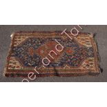 A small middle eastern wool rug with geometric patterns in predominantly dark blue, red and white,