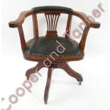 An Edwardian oak and leather swivel office chair with pierced splat back