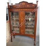 An Art Nouveau inlaid mahogany display cabinet, the low raised back with typical inlaid detail and