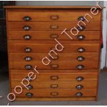 An early 20th Century light oak sectional map chest of nine long drawers with original metal cup