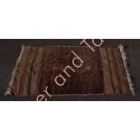 An Afghan Belouch wool rug in predominantly brown and blue, 141cms x 81cms