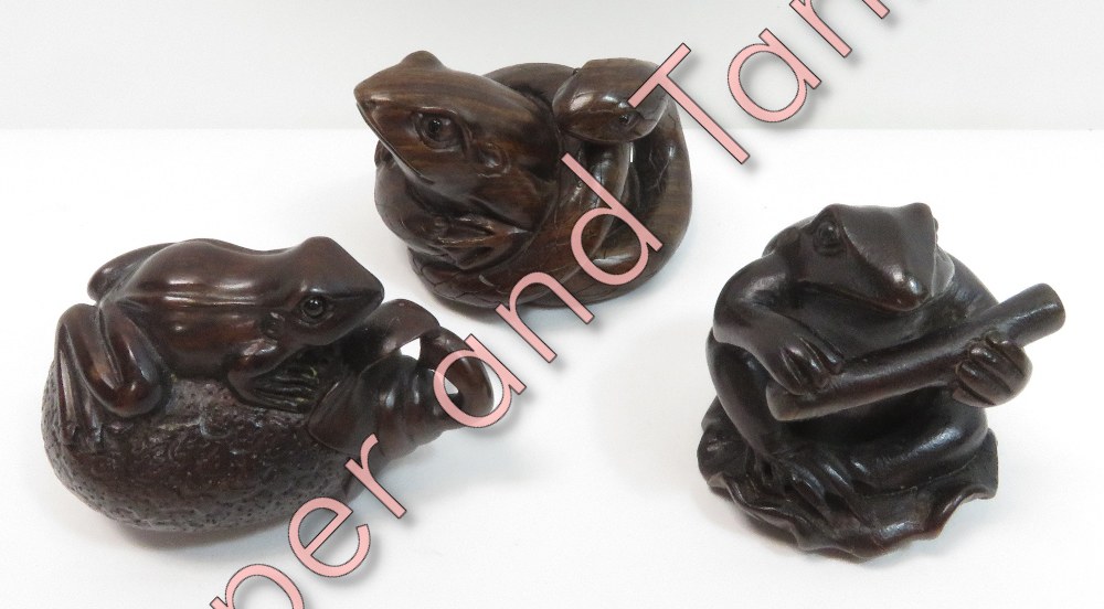 Three reproduction carved hardwood netsukes - a frog and snake; a frog holding a stick and a frog on