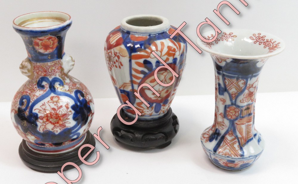 Two small Japanese Imari vases on hardwood stands, 11.5cms and 12cms high and an ovoid Imari vase