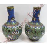 A pair of Japanese cloisonné bottle shaped vases having trailing floral and foliate decoration on