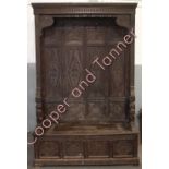 A large Victorian carved oak hall settle, having high back fitted with a row of clothes pegs, the