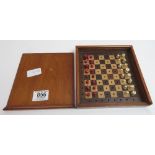 An early 20th Century travelling chess set with ivory and stained ivory chess men on wooden “peg”