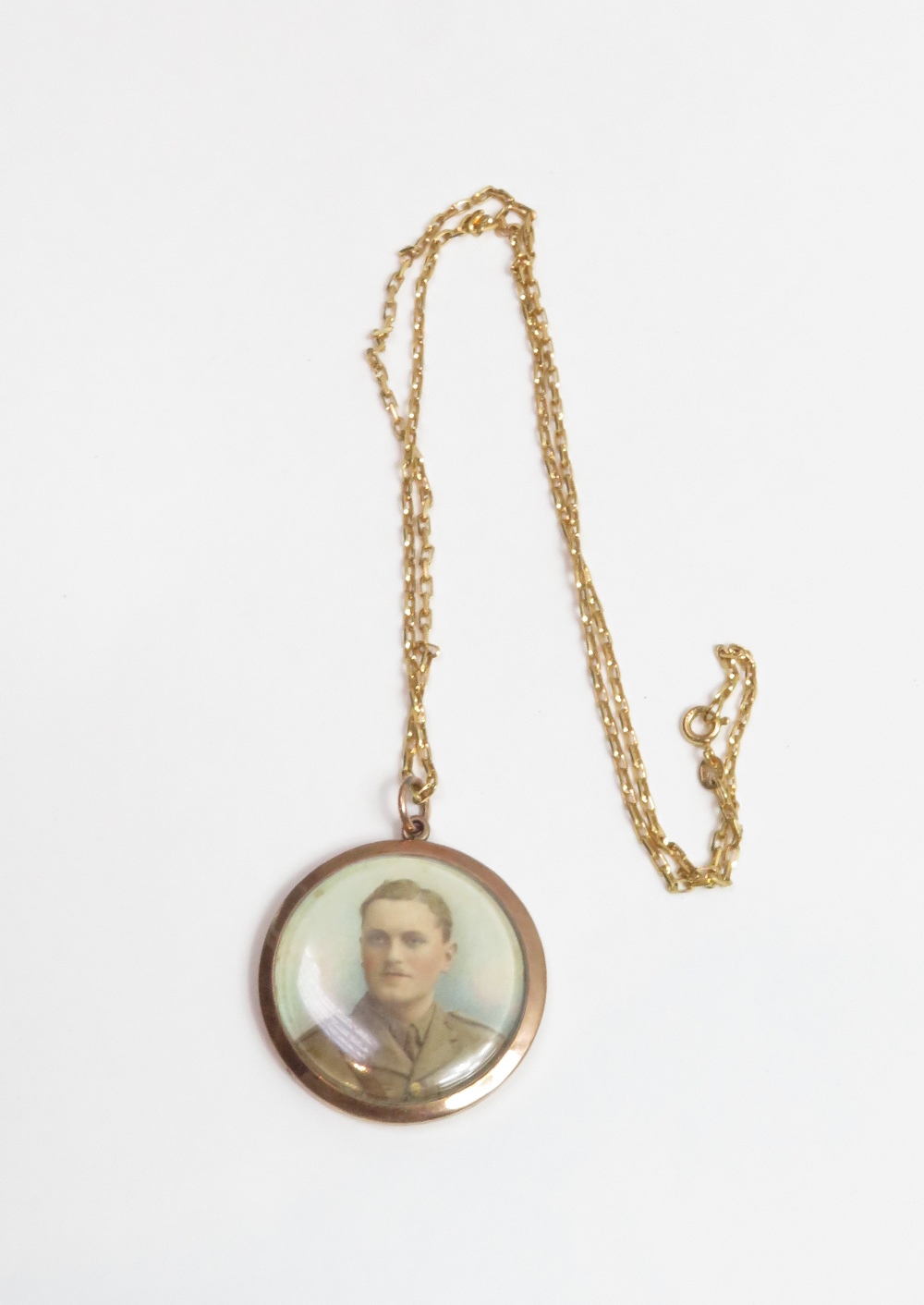 A picture pendant, circa 1918, stamped '9ct' to the jump ring, mounted with a hand coloured