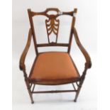 An early 20th Century open arm carver chair having pierced splat, curving arms and turned front