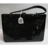 A c.1950's black patent crocodile leather handbag with leather fitted interior and gilt metal clasp