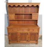 An Old Charm type light oak dresser the upper section with shelves and small cupboards, the base