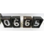 Four rectangular black painted metal boxes each containing numerals which flick over when a lever is