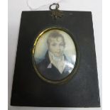An early 19th Century oval miniature portrait of a young man on ivory panel and in original black