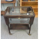 A mid 20th Century oak tea trolley the upper section with bevelled glass panels, the sides all