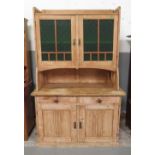 A stripped pine kitchen dresser the upper section with pair of doors having textured green glass