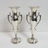 A pair of loaded silver vases, by H. Matthews, Birmingham 1912, with scroll handles, 15.7 cm high