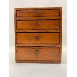 A 20th century pine cabinet of four graduated drawers, 30cm high, 25cm wide, 31.5cm deep