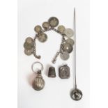 A hat pin with a silver thistle finial; a silver bell from a childs rattle; a silver thimble; a