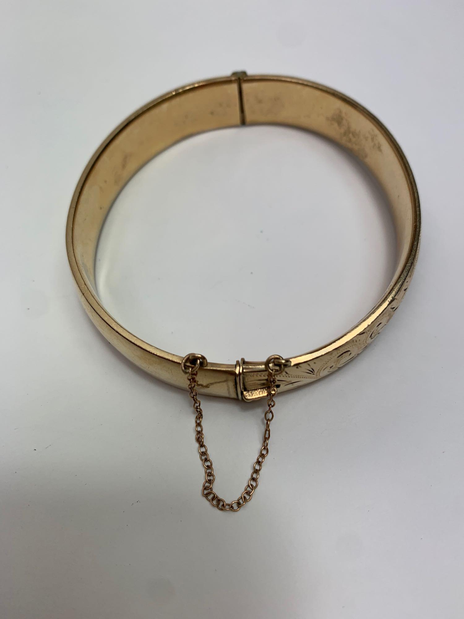 A gilt metal hinged bangle, with half engraved decoration, inner diameter 5.8 cm