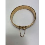 A gilt metal hinged bangle, with half engraved decoration, inner diameter 5.8 cm