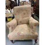 A Victorian open armchair upholstered in floral fabric with turned front legs and block bag legs;